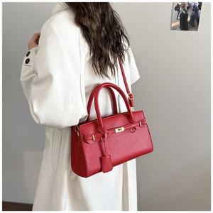 Vue détaillée du sac en cuir rouge à grain litchi avec boucle dorée sur trench blanc