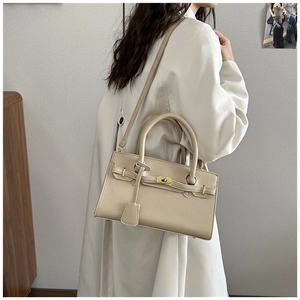 Détail d'un sac à main beige en cuir grainé avec fermoir doré porté en bandoulière chic