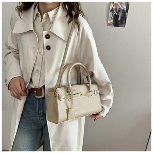 Sac à main en cuir beige à motif litchi porté par un mannequin en manteau élégant