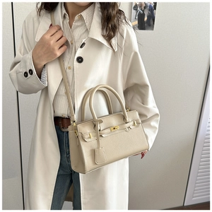 Détail du sac à main en cuir grainé beige avec fermoir doré et bandoulière amovible