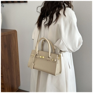 Détail du sac Kelly en cuir beige avec fermoir doré porté au dos par un modèle