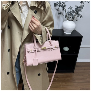 Détail du sac à main en cuir grainé rose avec fermoir rotatif doré et lanière décorative