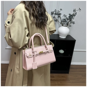 Détail du sac à main rose en cuir grainé avec fermoir doré et bandoulière amovible