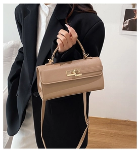 Close-up of light brown textured leather handbag with gold metal twist-lock and top handle