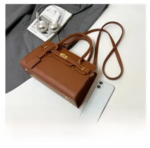 Détail d'un sac à main en cuir marron grainé avec boucle dorée et bandoulière amovible