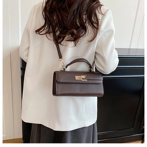 Vue détaillée d'un sac bandoulière en cuir marron foncé avec fermoir rotatif doré sur modèle