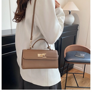 Gros plan d'un sac à main marron avec boucle dorée porté par une femme élégante