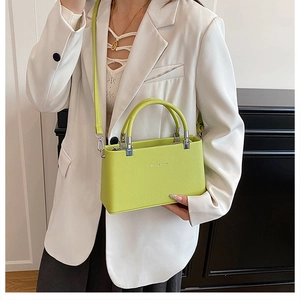 Detailed view of lime green lychee grain leather crossbody bag with silver hardware on model