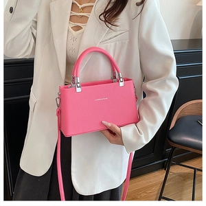 Detail of hot pink lychee leather square bag with silver hardware on a white blazer
