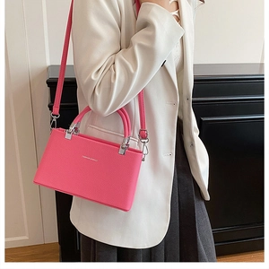 Detailed view of pink lychee leather handbag with silver hardware on model in white suit