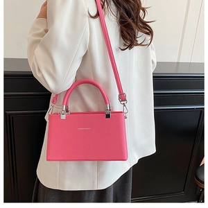 Model wearing a peach pink crossbody bag with litchi texture and silver hardware