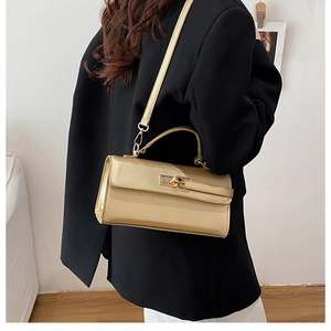 Détails d'un sac à main doré métallisé avec texture croisée et fermoir pivotant raffiné
