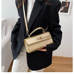 Détail d'un sac à main doré structuré avec finition métallique et fermoir sur un blazer