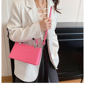 Bright pink pebbled leather handbag shown on model with stylish white blazer outfit