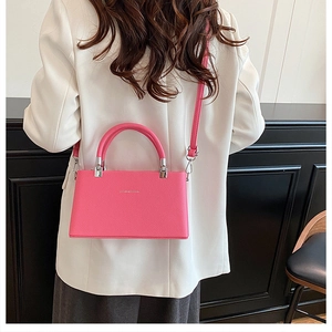 Detail of pink lychee leather crossbody bag with silver hardware on model