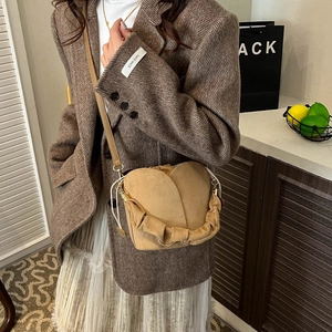 Camel suede bucket bag with drawstring and pleated handle worn with a brown blazer