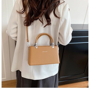 Rear view of a model wearing a camel lychee leather crossbody bag with silver hardware