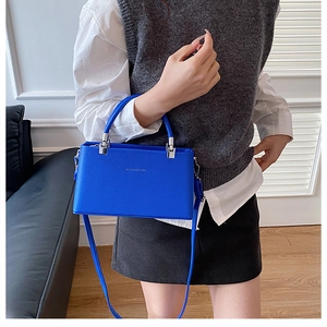 Detail of blue leather handbag with lychee texture and silver metal handle accents