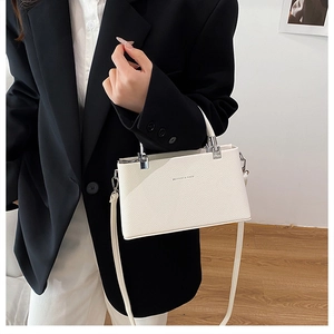 Close-up of white lychee textured crossbody bag with silver hardware and detachable strap