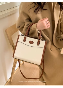 Detail of retro cream and brown leather tote bag held by model in warm indoor setting