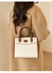 Model wearing a retro cream and brown crossbody bag with a minimalist wool coat