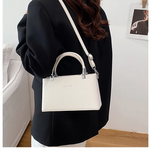 Close-up of a white lychee leather box bag with a top handle and adjustable shoulder strap