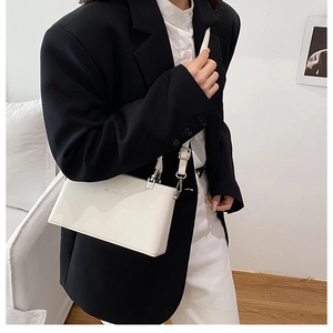Close-up of white lychee leather texture and metal buckle on the square crossbody bag