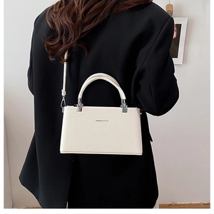 Creamy white lychee leather handbag with silver hardware shown on black blazer