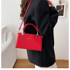 Close-up of red lychee grain leather handbag with gold lettering and silver hardware