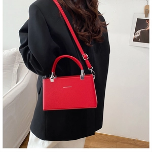 Detail of red textured leather handbag with silver hardware and fashion lettering