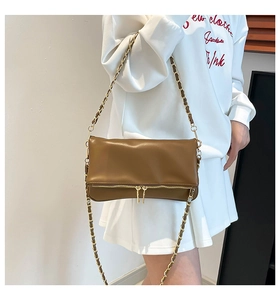 Detalle de bolso de hombro en cuero marrón con cadena dorada y doble cremallera