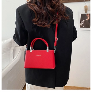 Detail of red textured leather crossbody bag with silver hardware and fashion lettering