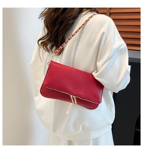 Detalle de bolso de hombro rojo en cuero con cadena dorada y cremallera metálica