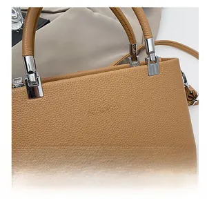 Close-up of litchi grain leather texture and metal buckle on light brown handbag