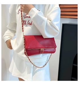 Detalle del bolso bandolera de piel roja granulada con cremalleras dobles doradas