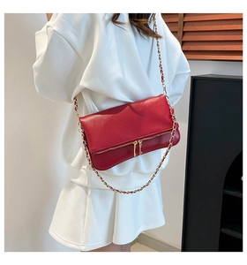 Bolso de hombro en cuero granulado rojo con cadena dorada usado por una modelo
