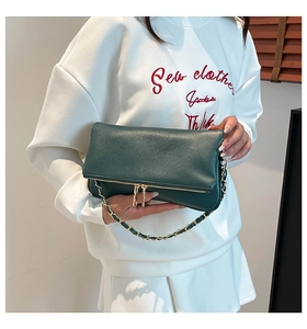 Detalle de bolso de hombro en cuero verde oscuro con cadena dorada y adornos de cremallera