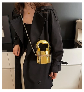 Detail of gold mirror finish cylindrical bucket bag with metallic handle and chain strap