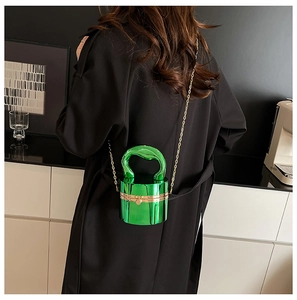 Detail of emerald green cylindrical acrylic bag with gold handle and chain strap