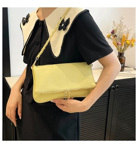 Detalle de un bolso de hombro en cuero granulado amarillo brillante con cadena dorada