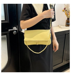 Detalle de bolso bandolera amarillo en cuero granulado con cremallera dorada y cadena