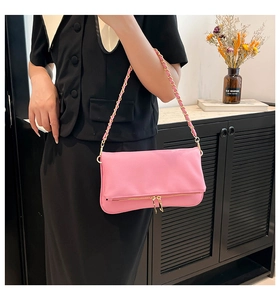 Vista de detalle del bolso con solapa de cuero rosa con cremalleras doradas y cadena