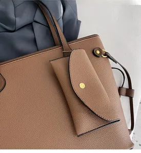 Gros plan d'un sac cabas marron en cuir grainé avec bouton doré et petite pochette