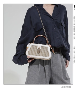 Detail of woven straw box bag with decorative silk scarf handle and gold chain strap