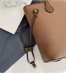 Gros plan d'un sac cabas en cuir marron à motif litchi avec anneau en métal doré