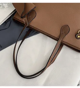 Détail du sac cabas en cuir marron à motif litchi montrant les anses et les boucles dorées