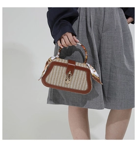 Detailed close-up of woven straw bag featuring silk scarf handle and metal ring lock