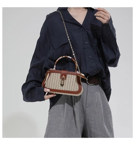 Detail van geweven crossbodytas met bruine lederen bies, zijden sjaal en gouden ketting