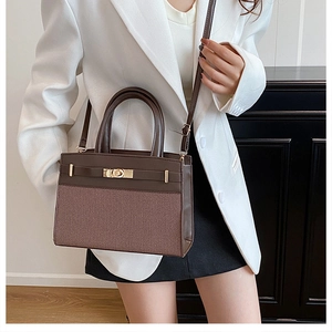 Detail of a brown patchwork handbag featuring textured leather, fabric, and gold clasp