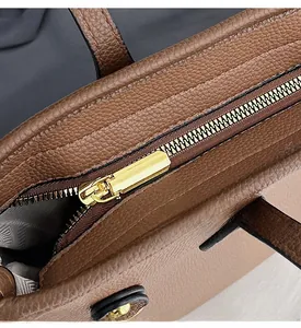 Gros plan sur la fermeture éclair dorée et le cuir grainé du sac fourre-tout brun